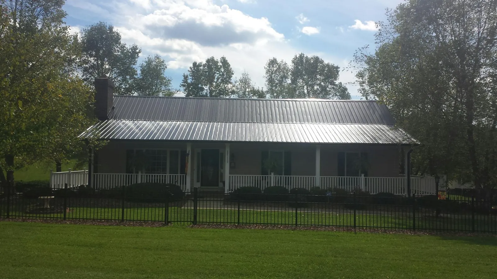 Gray metal roof on a brick ranch with a full width front porch — Gutter Guard Installation work by our crew in Fishers