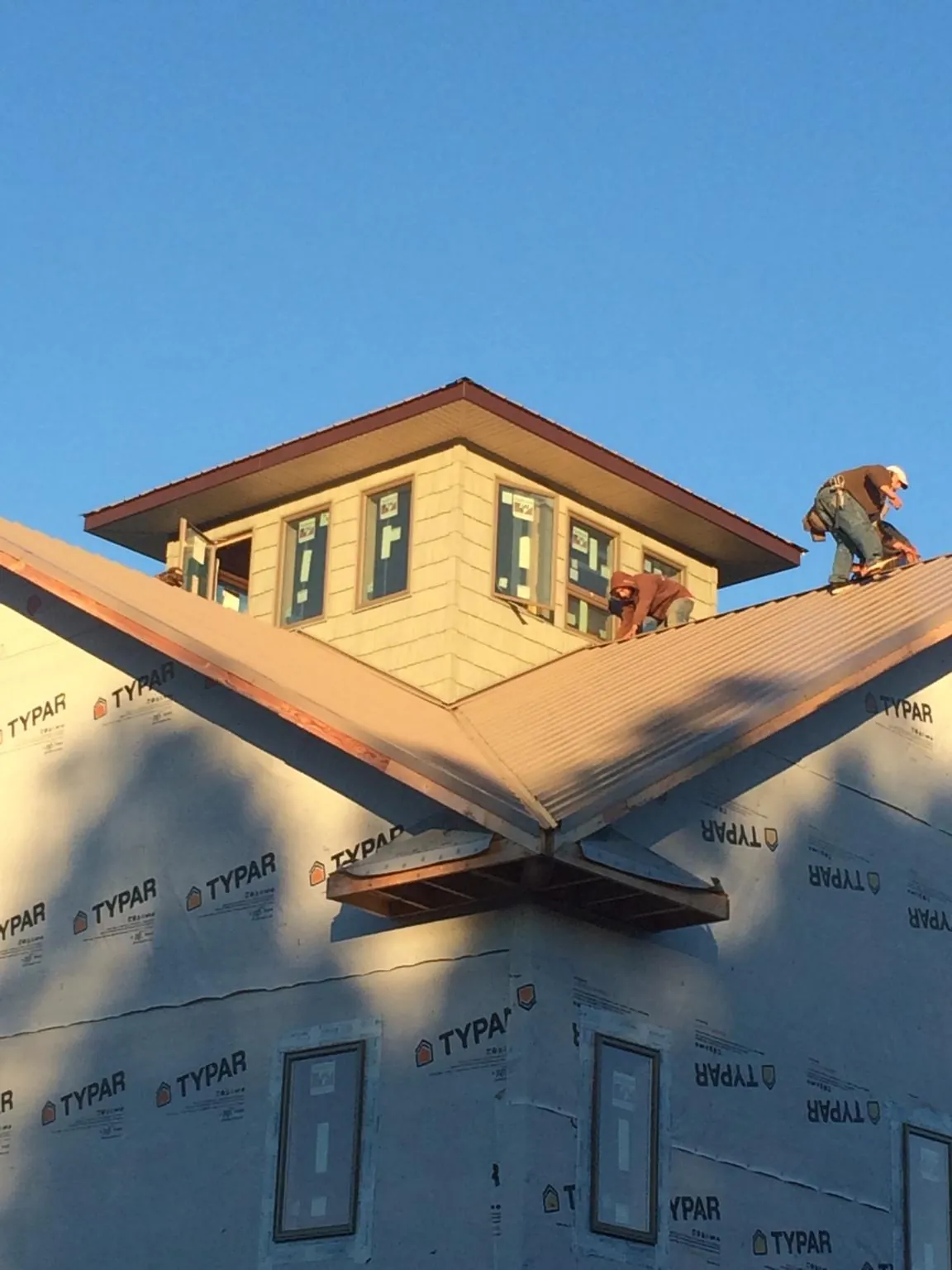 Roofers working around a rooftop cupola on a new metal roof at sunset — Roof Waterproofing in Fishers by Roofing Brothers